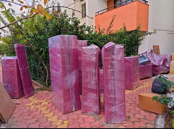 Furniture stretch-wrapped in pink film, standing upright in a garden