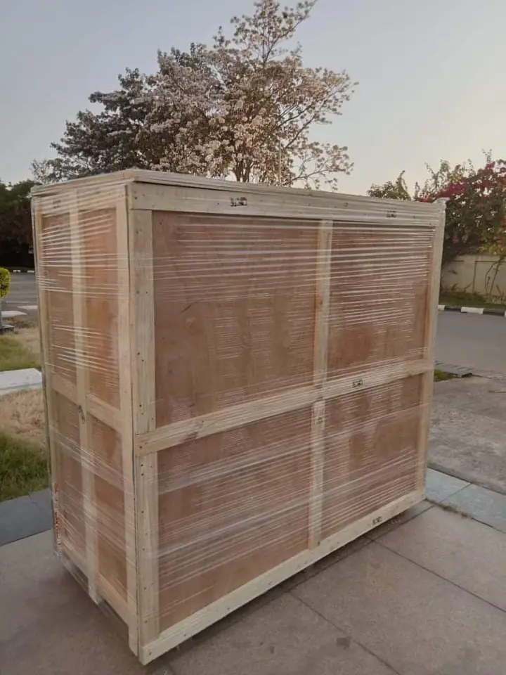 A wooden crate built around a large item, standing outside