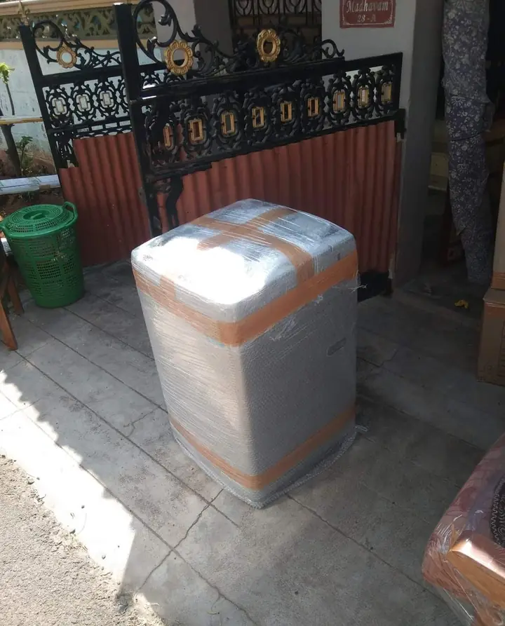 An appliance wrapped in stretch film and tape near a gate