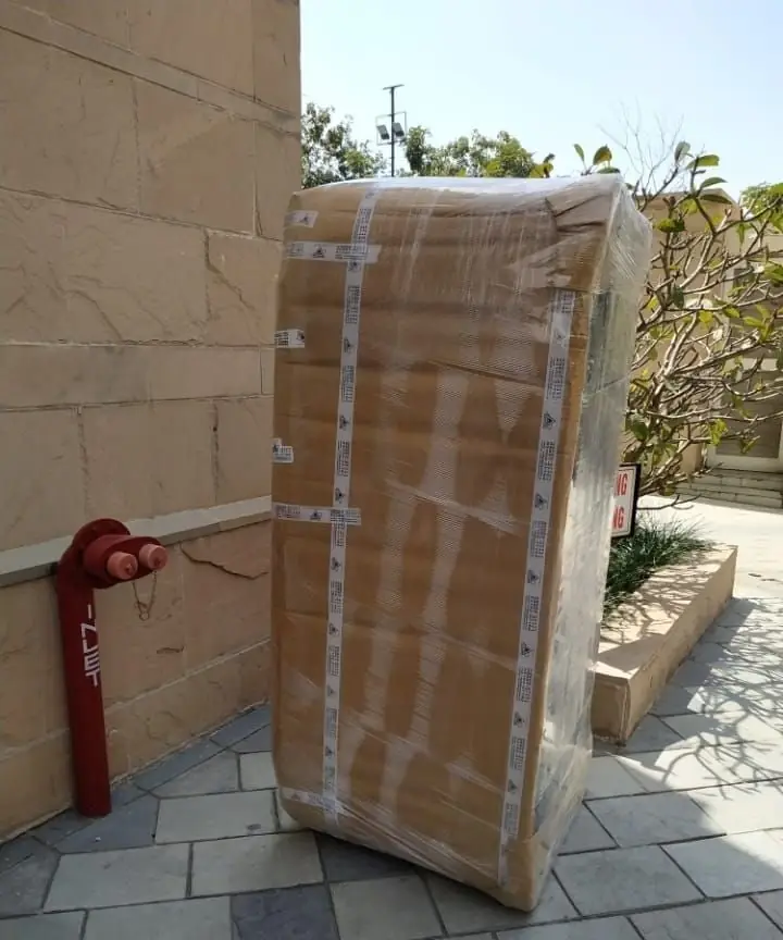 A tall cupboard wrapped in cardboard and stretch film outside